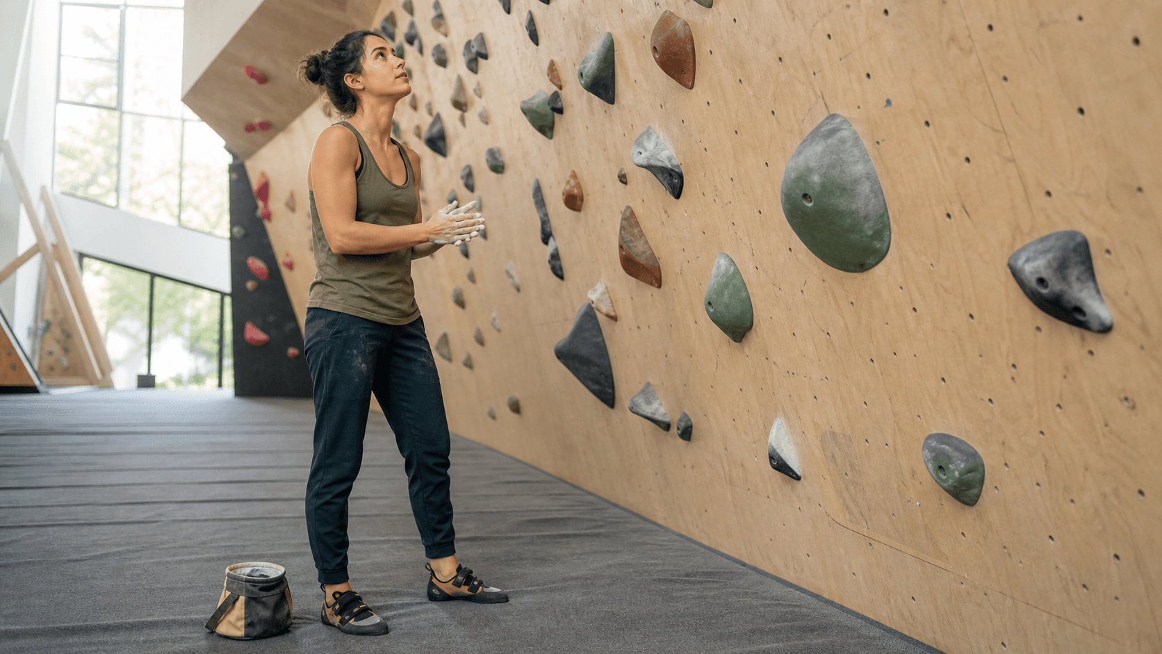 Confident woman preparing to climb a route at a bright indoor bouldering gym