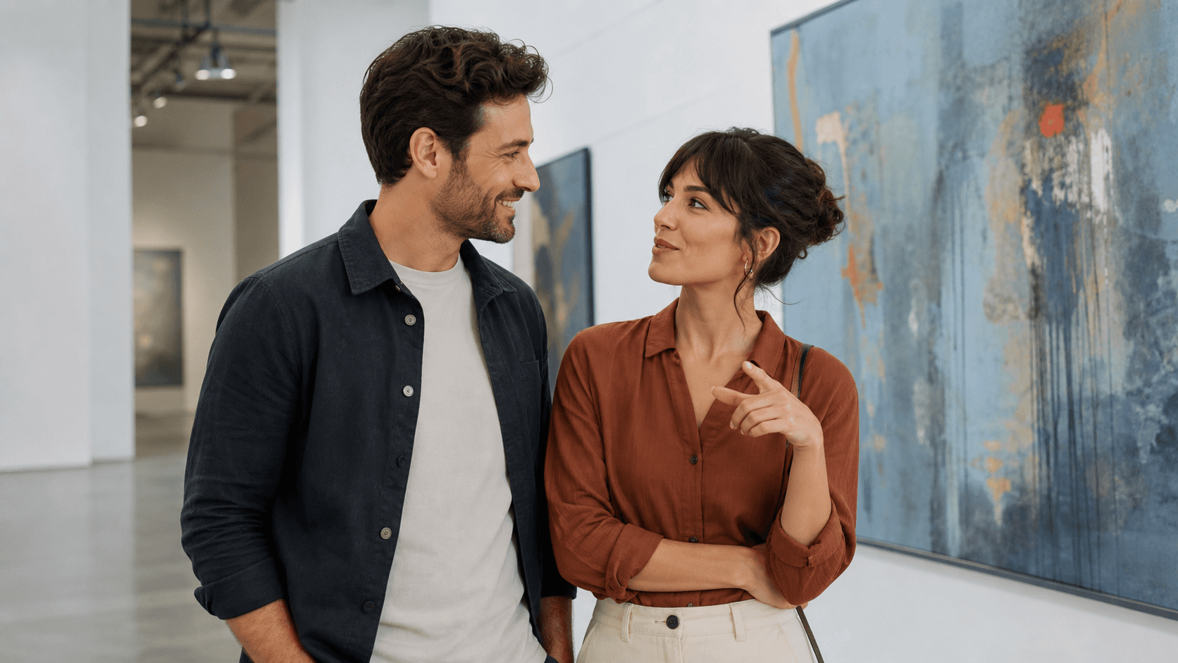 A woman and man share playful eye contact and an engaging conversation during a relaxed art-gallery date.